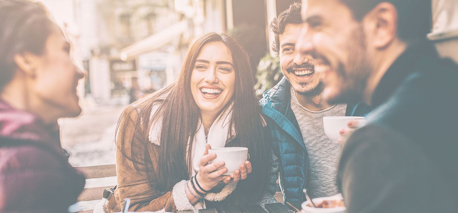 Friends chatting and laughing over coffee at an outdoor cafe